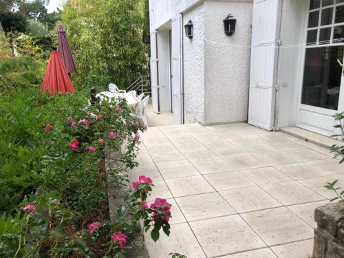 拉波勒Villa 10-12 pers centre La Baule 300m de la Mer的庭院里种着粉红色的鲜花,配有遮阳伞