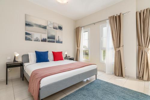 迪拜Lux BnB Springs Villa Private Garden的一间卧室配有一张带蓝色和红色枕头的大床