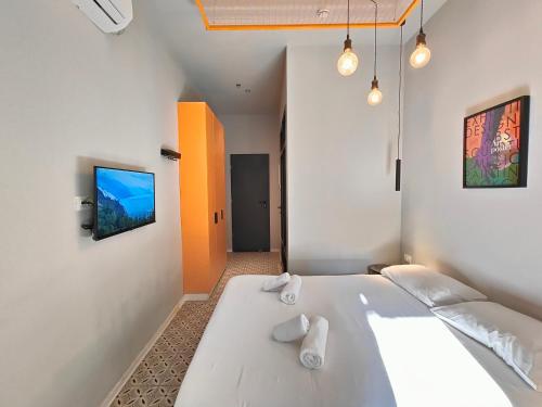 特拉维夫Levinski Market Hotel的卧室配有一张白色大床和一台平面电视。