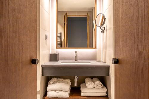 巴黎Le Bellune Paris的浴室配有盥洗盆、镜子和毛巾