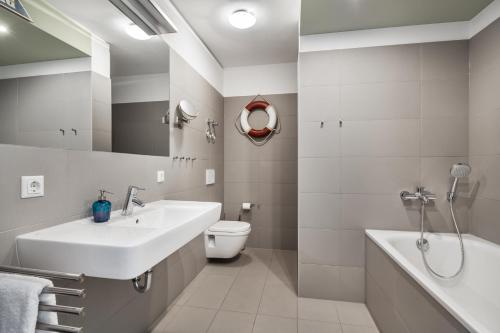 埃肯弗德Apartmenthaus Hafenspitze Ap 5 - "am Yachthafen 5" - Blickrichtung offenes MeerStrandpromenade - a72320的浴室配有盥洗盆、卫生间和浴缸。