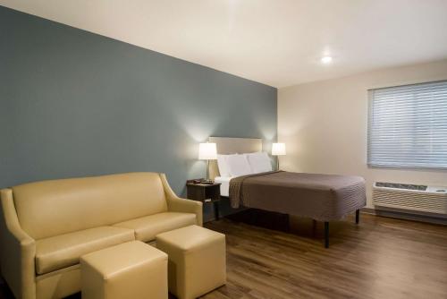 杰克逊维尔WoodSpring Suites Jacksonville - South的酒店客房配有床、沙发和椅子