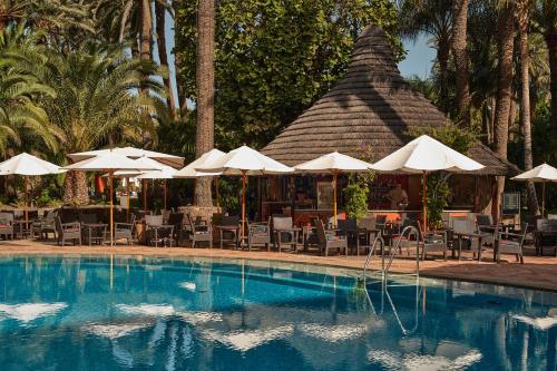 马斯帕洛马斯海滨棕榈滩酒店的一个带遮阳伞和椅子的游泳池以及一间餐厅