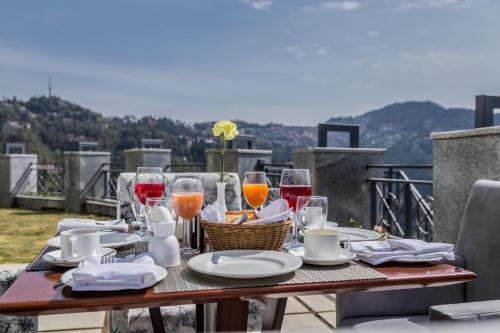 西姆拉The Zion Shimla的阳台上的桌子上摆放着葡萄酒和食物
