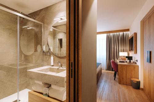 布勒伊-切尔维尼亚Valtur Cervinia Cristallo Ski Resort的一间带水槽和玻璃淋浴的浴室