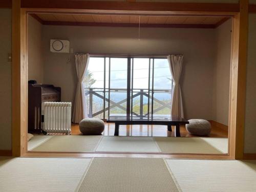 那须町HARUNA SKY Panoramic view of Nasu,private space surrounded by fir trees,relaxing stone bath,watching movies on a 120inch big screen的客厅设有桌子和大窗户