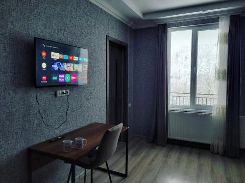 博尔若米White House In Borjomi的一间设有桌子和墙上电视的房间