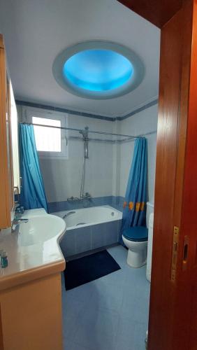 斯巴达Makarios Apartment Near Athens Aiport的带浴缸和卫生间的浴室以及蓝色天花板。