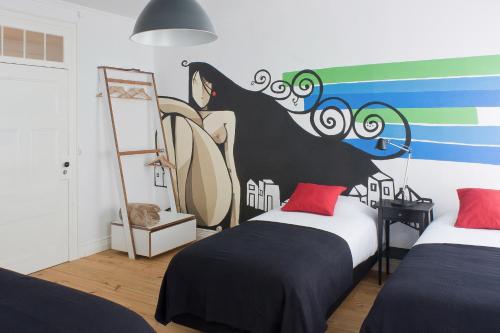 蓬塔德尔加达Azorean Urban Lodge的一间卧室设有两张床,墙上挂着一幅画