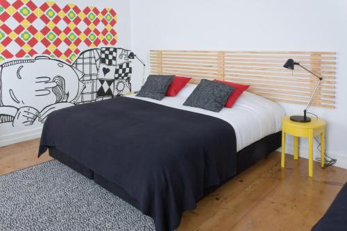 蓬塔德尔加达Azorean Urban Lodge的一间卧室配有一张带黑色毯子和红色枕头的床。