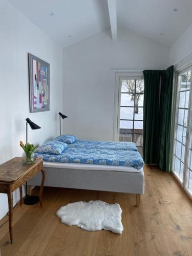 胡斯克瓦纳Gisebo Vingård的一间卧室配有一张床、一张桌子和一个窗户。