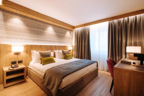 布勒伊-切尔维尼亚Valtur Cristallo Ski Resort, Dependance Cristallino的配有一张床和一张书桌的酒店客房
