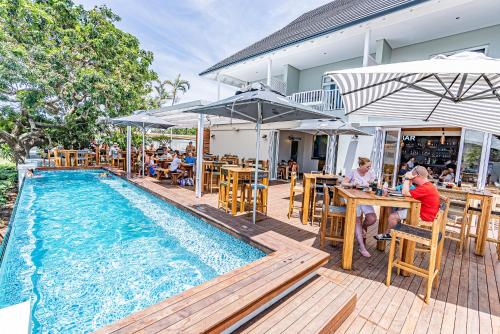 巴利托Beach Wood Boutique Hotel & Resort的一群人坐在游泳池旁的桌子上