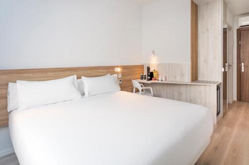奥埃拉斯B&B HOTEL Lisboa Oeiras的卧室配有一张白色大床和一张书桌