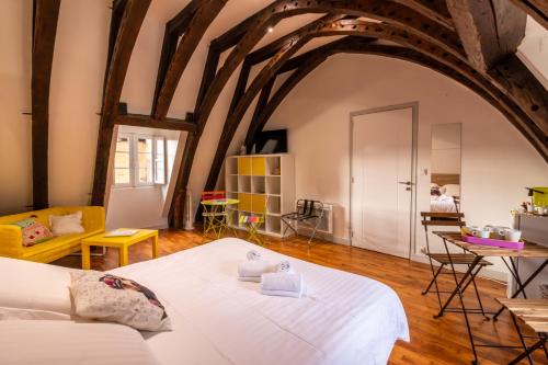 萨尔拉拉卡内达Les Chambres du "Coup de Coeur de Sarlat"的一间带一张白色大床的卧室,位于带木制天花板的房间内