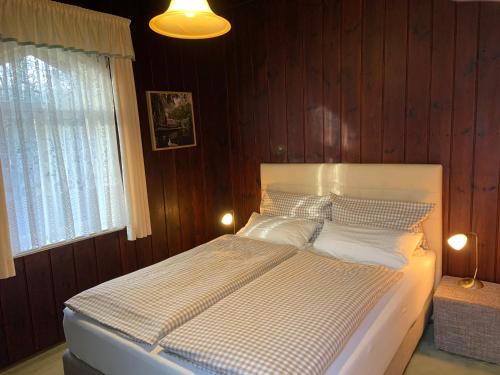 KaupenLogierhaus Lehde的卧室配有白色的木墙床
