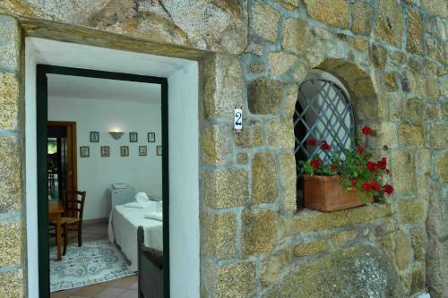 阿尔扎凯纳Lu Pastruccialeddu的石墙,有窗和一盆鲜花