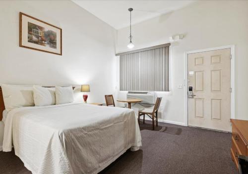 爱迪生Edison Motor Lodge的卧室配有白色的床和桌椅