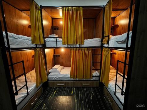 阿斯塔纳Flats Hostel的客房设有两张双层床和黄色窗帘