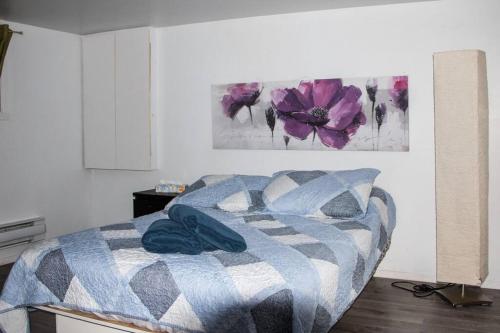 滨海圣吕斯Maison rose du bord de mer à 5 min de st Luce的卧室配有一张挂有花卉画的床铺。