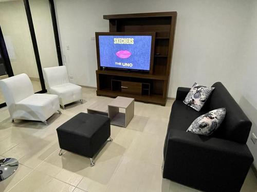 马尼萨莱斯Cómodo Apartamento en Manizales的客厅配有椅子和平面电视