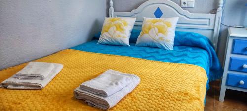 格兰阿利坎特Bungalow Deluxe Gran Alacant的一间卧室配有黄色的床、毛巾和枕头
