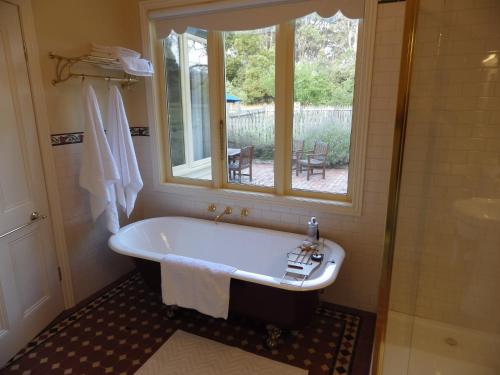 AshbourneThe Retreat at Amryhouse的带浴缸的浴室和窗户。