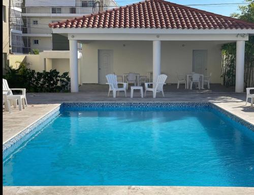 拉罗马纳Beautiful Condo in La Romana with pool near Caleta Beach的一个带椅子和桌子的游泳池以及一座房子