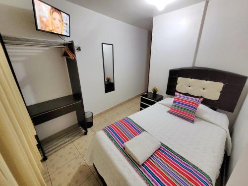 奥兰太坦波Hostal EL VIAJERO en Ollantaytambo的一间卧室配有一张带条纹枕头的大床
