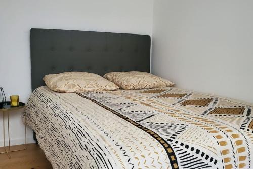 OsnyTulsa Home - Superbe appartement de deux chambres - avec terrasse privée的一张带黑色床头板的床和两个枕头