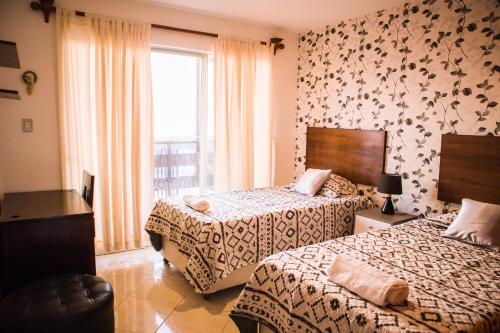 皮门特尔Hospedaje Casa Bonita Frente al Mar的酒店客房设有两张床和窗户。