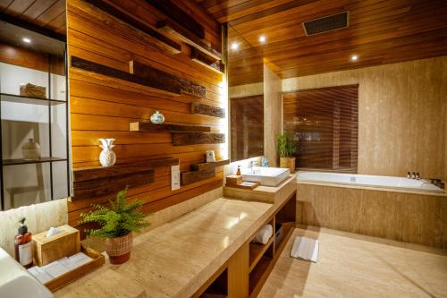库塔Crystalkuta Hotel - Bali的一间带木墙、浴缸和水槽的浴室
