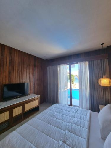 珀尼达岛Khamara Nusa Penida的一间卧室配有一张大床和电视