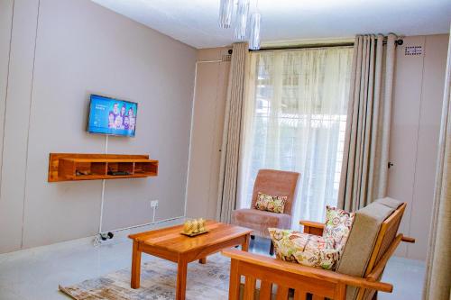 哈拉雷R Executive Apartments的客厅配有电视、桌子和椅子