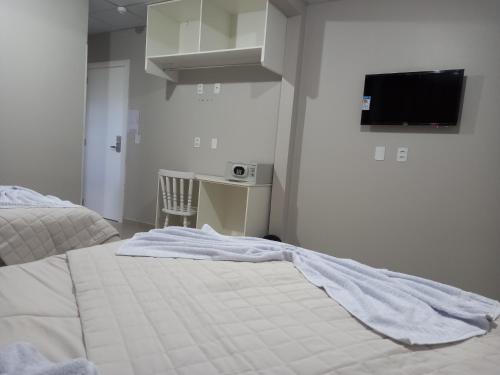 CaçadorSognare Hotel的一间卧室配有一张床、一张书桌和一台电视。