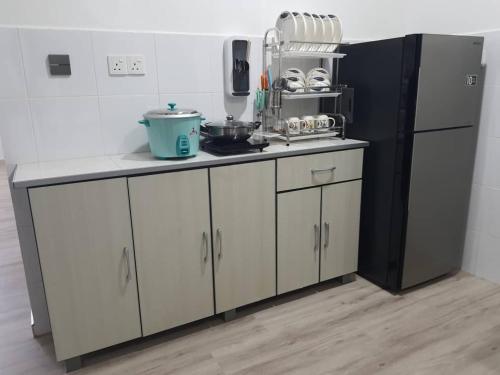 邦咯75 pangkor ocean的厨房配有白色橱柜和黑色冰箱。