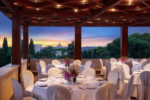 罗马Grand Hotel Gianicolo的宴会厅配有白色的桌椅,享有美景。