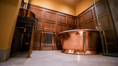 杜伦The Funky Monk的铜质浴缸,位于带木墙的房间内