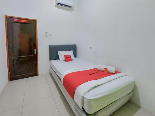SibengkokReddoorz at Cempaka Guesthouse Tarakan的一间小卧室,配有一张带红色毯子的床