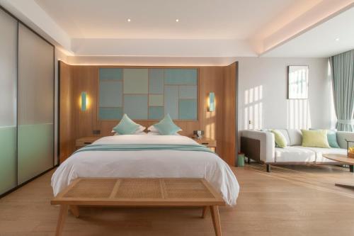 杭州之江印象君亭酒店(杭州转塘中国美院店）的一间卧室配有一张大床和一张沙发