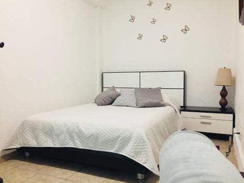 墨西哥城Department, Studio Type Excellent Location的卧室配有一张铺有白色床单的床和墙上的蝴蝶。