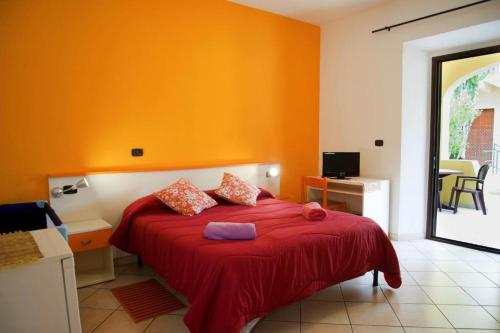 卡拉古诺内Affittacamere Casa del Sole的一间卧室设有橙色的墙壁和一张带红色毯子的床。