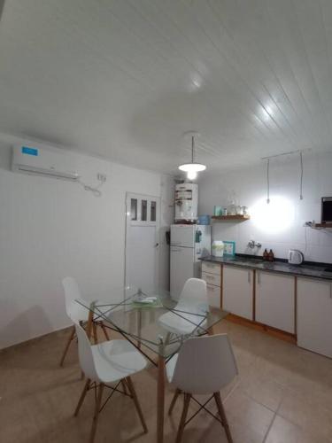 蒙特埃莫索Departamento para dos personas en Monte Hermoso.的厨房配有玻璃桌和白色椅子