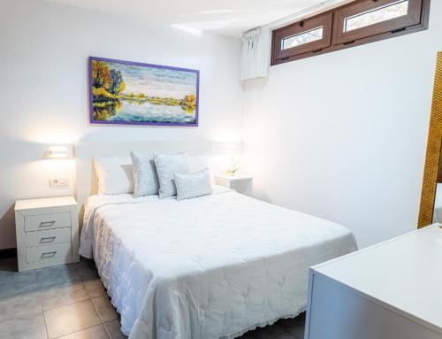 拉奥罗塔瓦Estancia Victoria的白色卧室配有一张床,墙上挂着一幅画