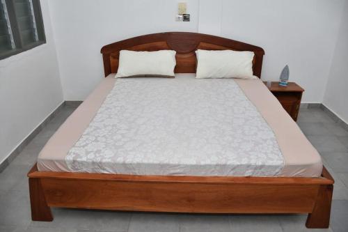 科托努Tranquillité Cotonou的卧室内的一张床铺,配有木制床架