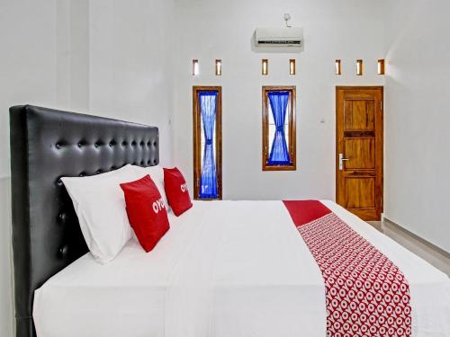 日惹Super OYO 92101 Elma Guesthouse的一间卧室配有红色和白色枕头的床