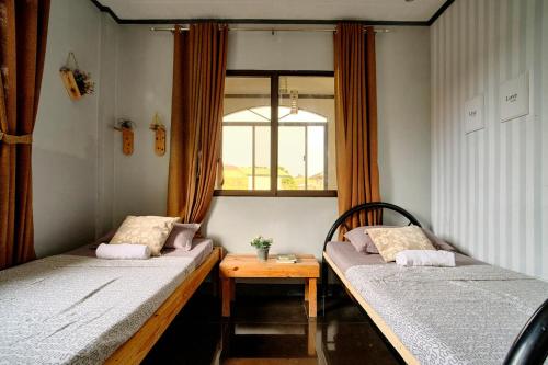伊洛伊洛Pallet Homes - Landheights的配有桌子和窗户的客房内的两张床