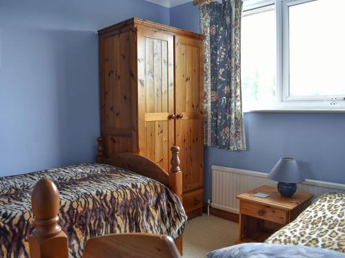 Preston麻雀鸟巢度假屋的一间卧室配有一张床和一个木制橱柜