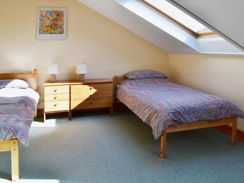 Soulby风海谷仓乡村别墅的阁楼卧室设有两张床和天窗