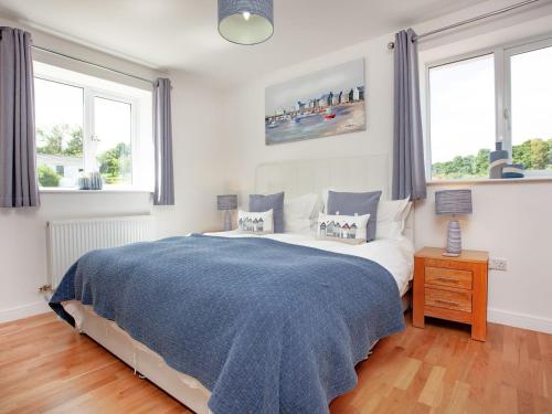 Cheriton Bishop圣丹斯度假屋的一间卧室配有一张带蓝色毯子的床和两个窗户。